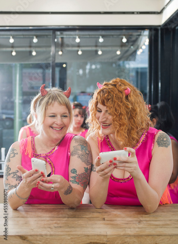 Women Wearing Devil Horns and Costumes Using Cellular Telephones, Oakland, Alameda County, California, USA photo