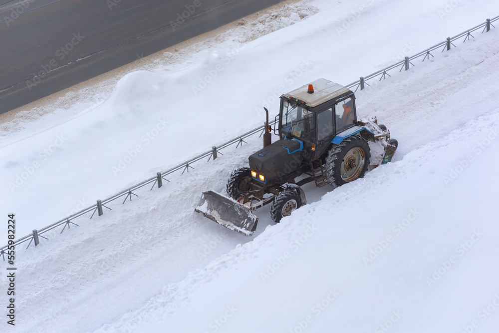The tractor with the help of a bucket cleans the pavement from snow. Snowblower. The tractor with the help of a bucket cleans the pavement from snow. Snowblower.