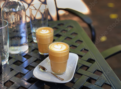 Two cortado coffees in glasses on outdoor, patio table with water bottle and glass, Canada photo