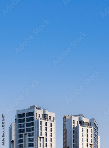 Front view of the top of two tall residential towers with blue sky and copy space