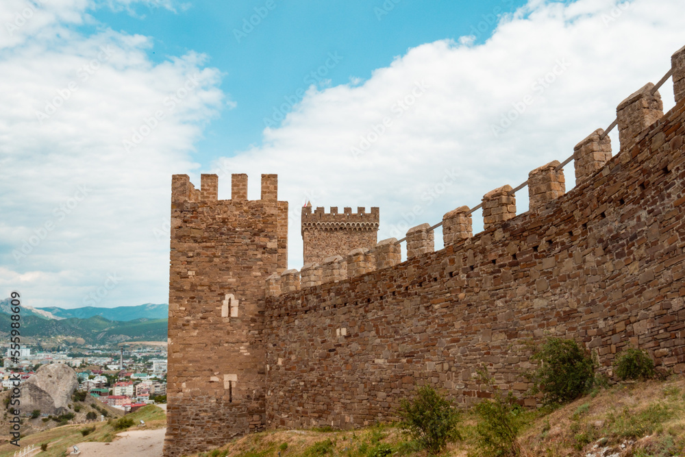 Part of the wall of the old fortress with towers and other stone structures. An old fortress against the blue sky. Part of the wall of the old fortress with towers and other stone structures. An old fortress against the blue sky.