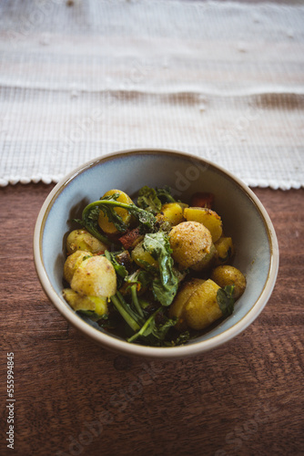 flatlay of potato stir-fried dish - natural linens and fresh herbs on a wooden table - healthy vegetarian dish