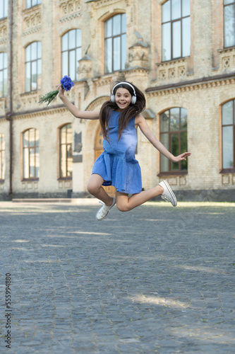 happy teen girl in headphones. girl jump outdoor. carefree girl jumping feel happiness