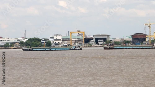 A group of boats tied in a row is pulled with cargo up the Chao Phraya River, Samut Prakan, Thailand, accelerated video photo