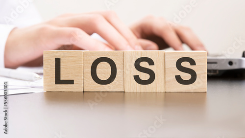 man made word LOSS with wood blocks on the background of the office table. selective focus. business concept.