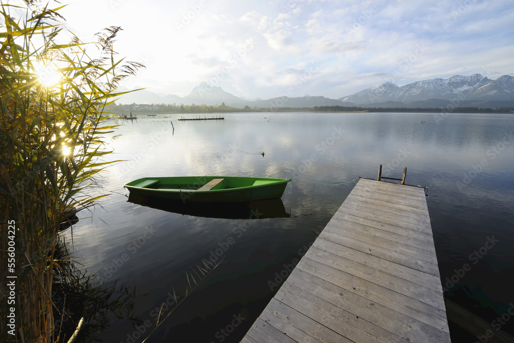 Wooden Jetty with Rowboat and Sun, Hopfen am See, Lake Hopfensee, Bavaria, Germany Wooden Jetty with Rowboat and Sun, Hopfen am See, Lake Hopfensee, Bavaria, Germany