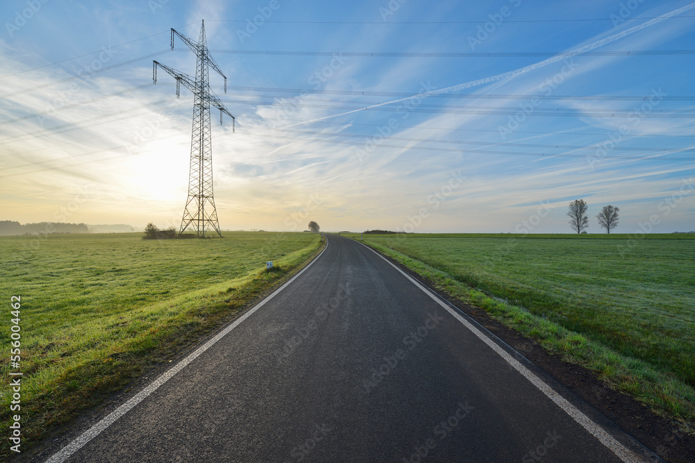 Country Road with Electricity Pylon in Morning with Sun, Freiensteinau, Vogelsbergkreis, Hesse, Germany Country Road with Electricity Pylon in Morning with Sun, Freiensteinau, Vogelsbergkreis, Hesse, Germany