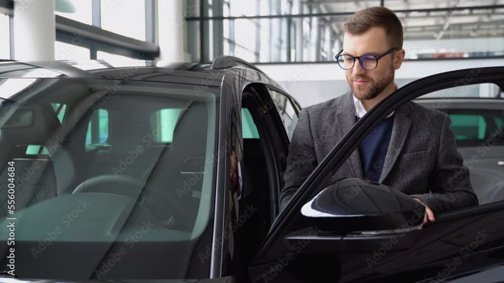 A stylish man in glasses and suit examine vehicle before making purchase. Buy car A stylish man in glasses and suit examine vehicle before making purchase. Buy car