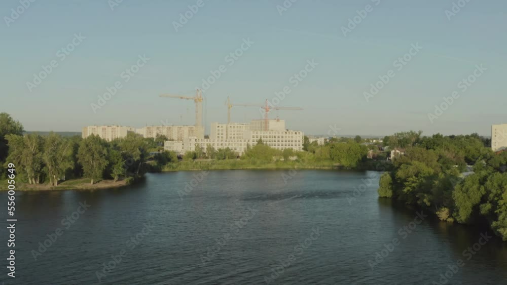 Construction site of large apartment complex with tower cranes on river bank bird eye view. City development process Construction site of large apartment complex with tower cranes on river bank bird eye view. City development process