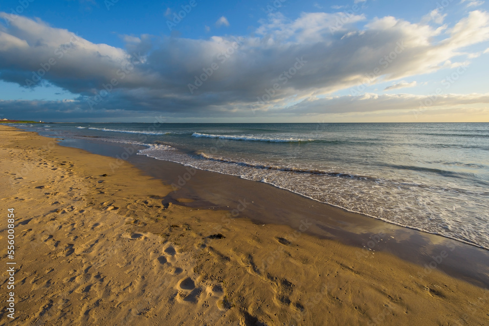 Sandy beach and dramatic clouds over the surf of the North Sea at Bamburgh in Northumberland, England, United Kingdom Sandy beach and dramatic clouds over the surf of the North Sea at Bamburgh in Northumberland, England, United Kingdom