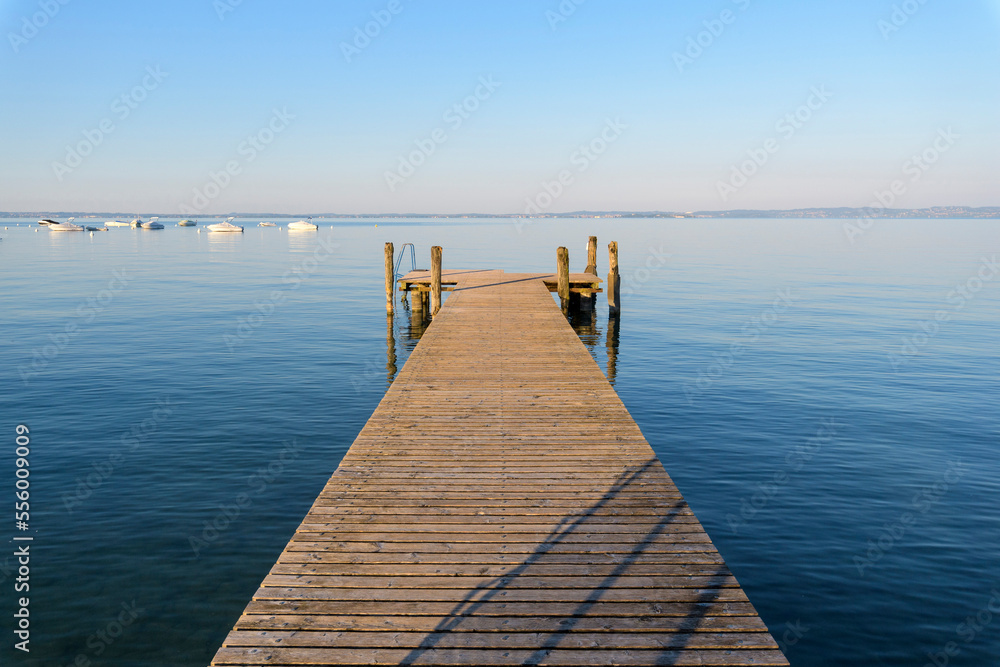 Wooden jetty on Lake Garda (Lago di Garda) on a sunny morning at Bardolino in Veneto, Italy Wooden jetty on Lake Garda (Lago di Garda) on a sunny morning at Bardolino in Veneto, Italy