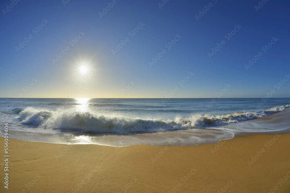Waves breaking on the shoreline of Ninety Mile Beach at Paradise Beach with the sun shining over the ocean in Victoria, Australia Waves breaking on the shoreline of Ninety Mile Beach at Paradise Beach with the sun shining over the ocean in Victoria, Australia