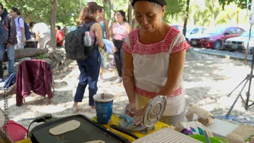 Yucatecan Woman in Traditional Mayan Huipil Clothing Making Tlayudas with Her Hands and Corn Dough on an Electric Grill. Pre-Hispanic Oval Shaped Mexican Dish Made of Masa like Quesadillas Huaraches photo