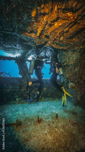 two scuba diver checking a small dome of air into a shipwreck