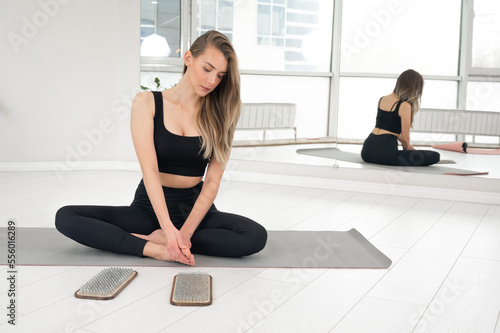 Caucasian woman sits on yoga mat after standing on sadhu nails.