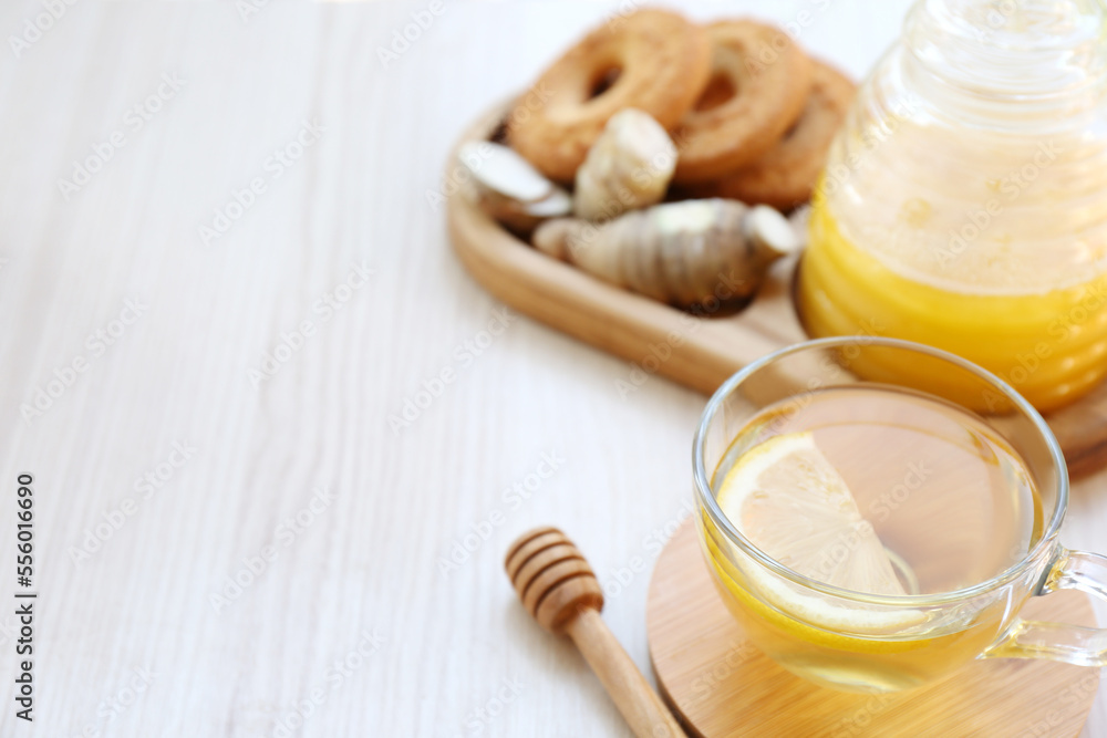 Cup of delicious tea with lemon, honey and ginger on white wooden table. Space for text Cup of delicious tea with lemon, honey and ginger on white wooden table. Space for text