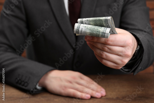 Man holding money at wooden table, closeup. Currency exchange