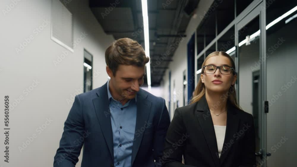 Two employees walking office together. Smiling specialists going client meeting Two employees walking office together. Smiling specialists going client meeting