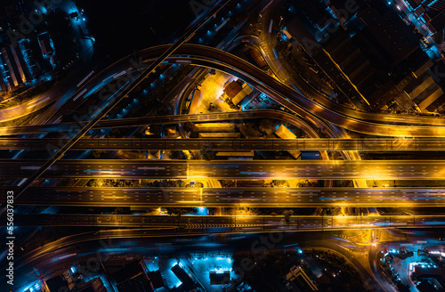 Aerial top view of Modern Multilevel Motorway Junction with Expressway, Road traffic an important infrastructure in Thailand. Bangkok urban Mass Transit Project (Pink Line Monorail). Night scene.