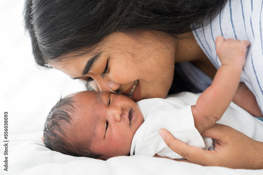 African American mother kissing her newborn baby on bed. Young mom or nurse taking care newborn in the hospital African American mother kissing her newborn baby on bed. Young mom or nurse taking care newborn in the hospital