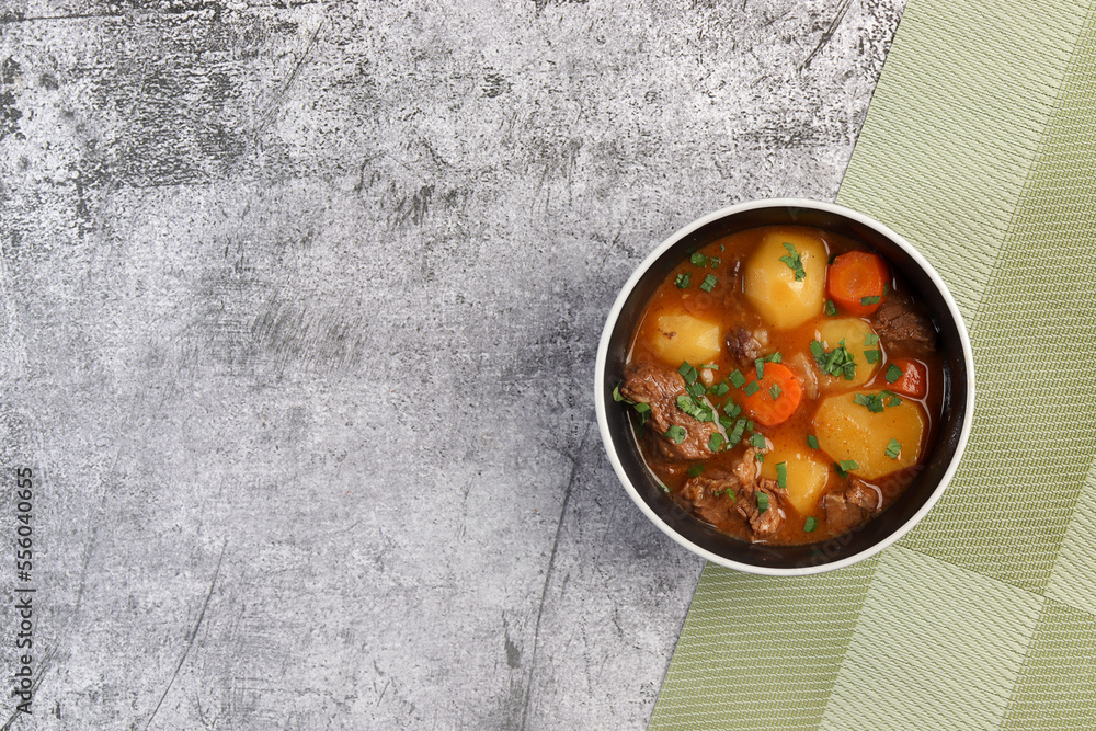 Beef Stew with Carrots, Potatoes and greens in a bowl on a dark background. Top view, flat lay . Beef Stew with Carrots, Potatoes and greens in a bowl on a dark background. Top view, flat lay .
