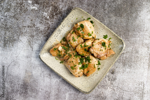 Oven Baked Garlic Chicken thighs with herbs on a square  plate on a dark background. Top view, flat lay