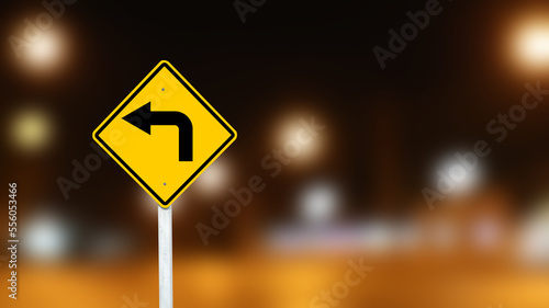 Yellow sign with left turn direction arrow on dark night blur background