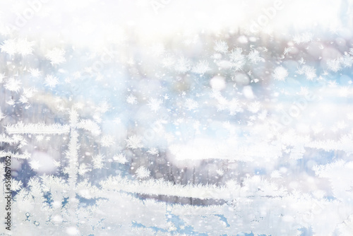 Winter landscape through a frozen window. Blurred snow background. Trees and plants covered with snow. © alexkich