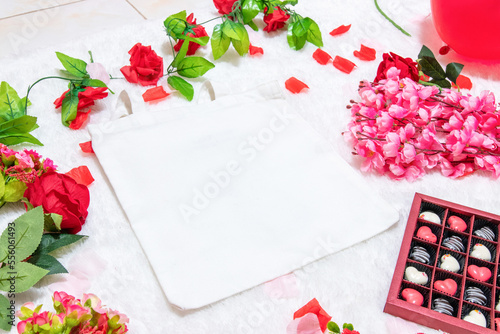 White blank tote bag on the top of a fluffy white carpet surrounded by valentine themed decorations