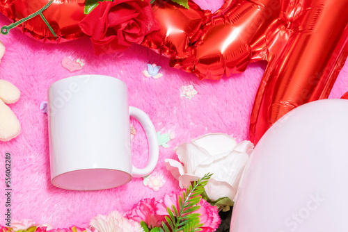 White blank coffee mug on the top of a fluffy pink carpet surrounded by valentine themed decorations