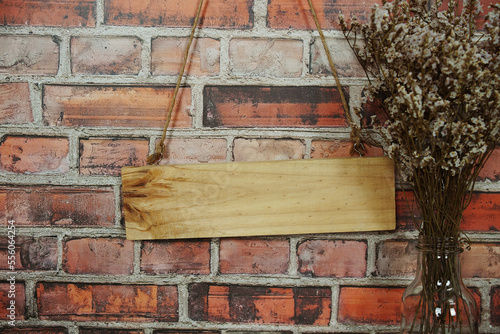 Empty space of Wooden sign hanging with rope and dried flower decoration on brick wall background © may1985