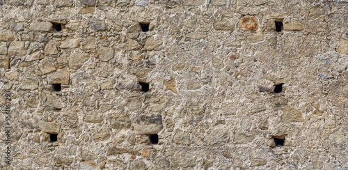 gray monochrone texture of an anciant old castle wall with little windows embrasures photo