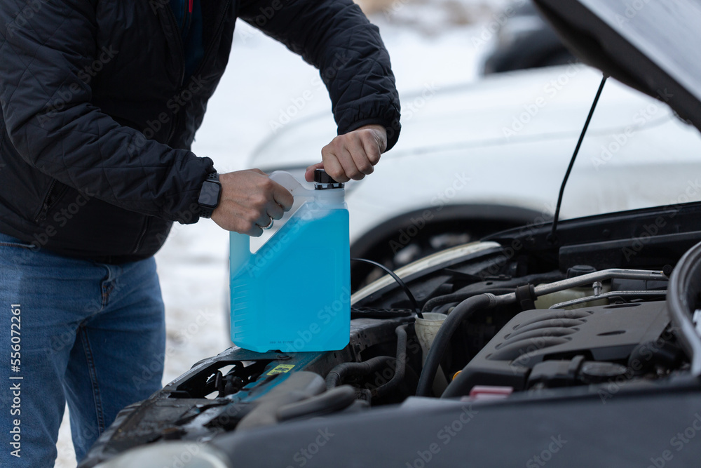 NonFreezing Liquid For The Car, Man opens the windshield washer fluid for the car Stock Photo