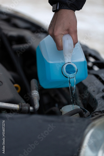 Non-Freezing Liquid For The Car, A man pours glass-washing liquid into the tank of a car