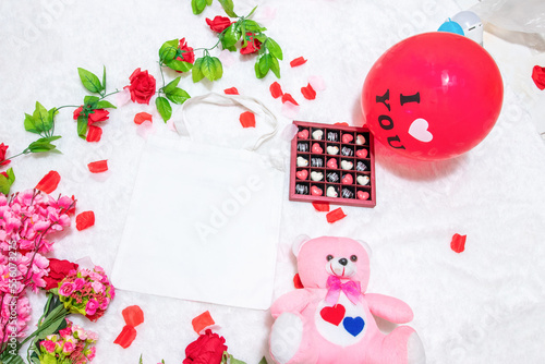 Fototapeta Naklejka Na Ścianę i Meble -  White blank tote bag on the top of a fluffy white carpet surrounded by valentine themed decorations