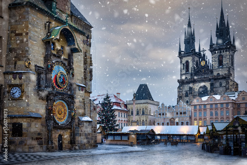 Winter view to the astronomical clock and the old town square of Prague with Tyn Church in the background and snow falling, Czech Republic photo