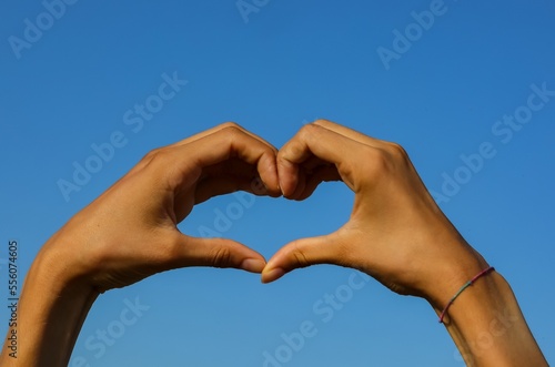 two joined hands forming the shape of a heart and the blue sky
