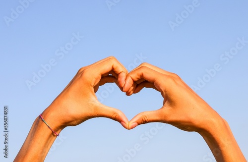 two joined hands forming the shape of a heart and the blue sky