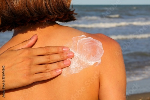 hand spreading skin protection sunscreen on little girl back