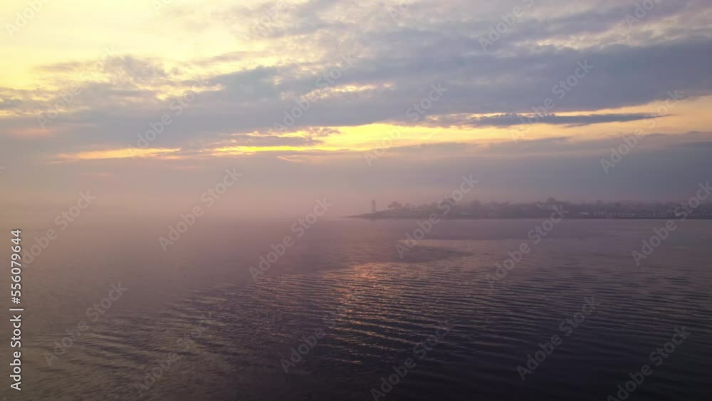 Drone over calm sea towards lighthouse at sunset Drone over calm sea towards lighthouse at sunset