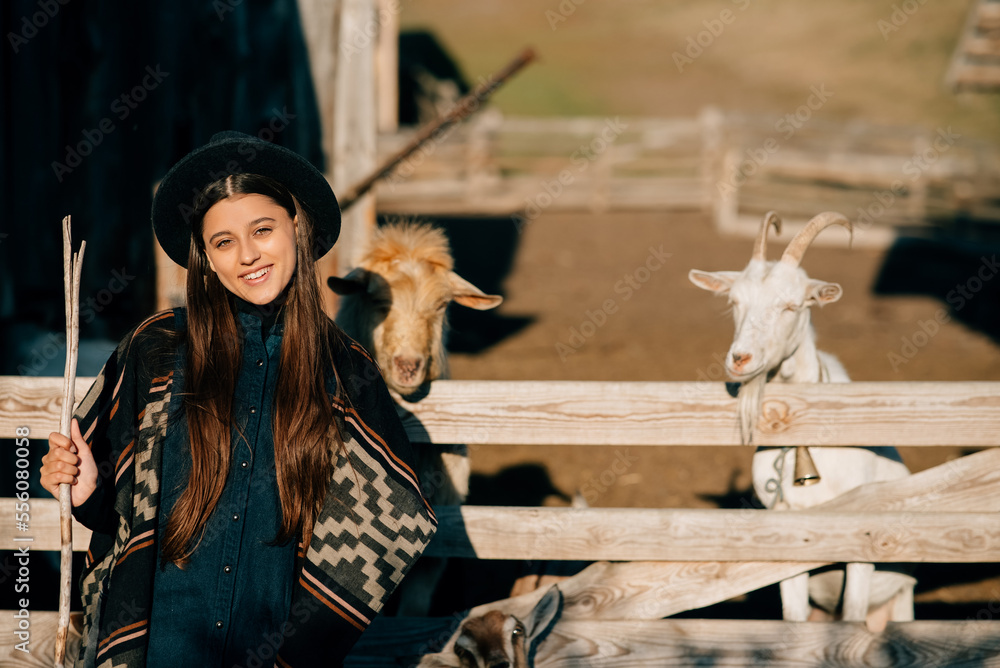 A young beautiful woman near a pen with goats