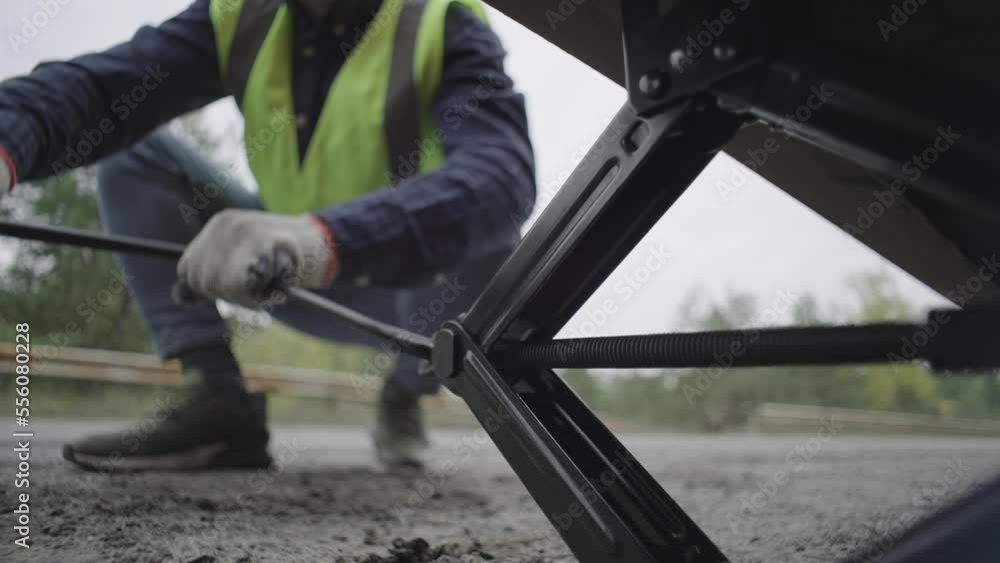 close-up of a man lifting a car with a jack. Breakdown of the car in the threshold on the car. High quality 4k footage close-up of a man lifting a car with a jack. Breakdown of the car in the threshold on the car. High quality 4k footage