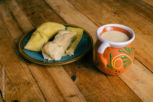 Tamales de elote and atole on a wooden table. Typical Mexican food. photo
