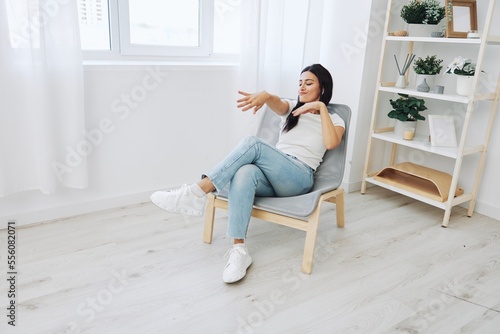 Woman sitting in chair listening to music on wireless headphones at home and dancing, fall lifestyle