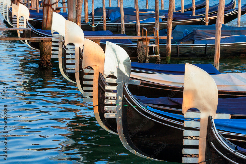 Venezia. Fila di gondole in sosta con riflesso sul ferro al tramonto