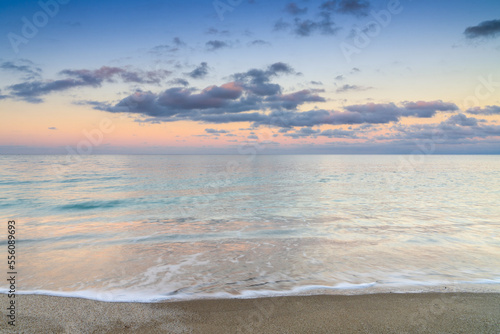 Fototapeta Naklejka Na Ścianę i Meble -  calm turquoise ocean water under a olorful sunset sky with calm waves on the sandy shore