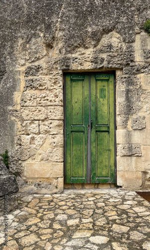 Closed old green wooden door in stone wall
