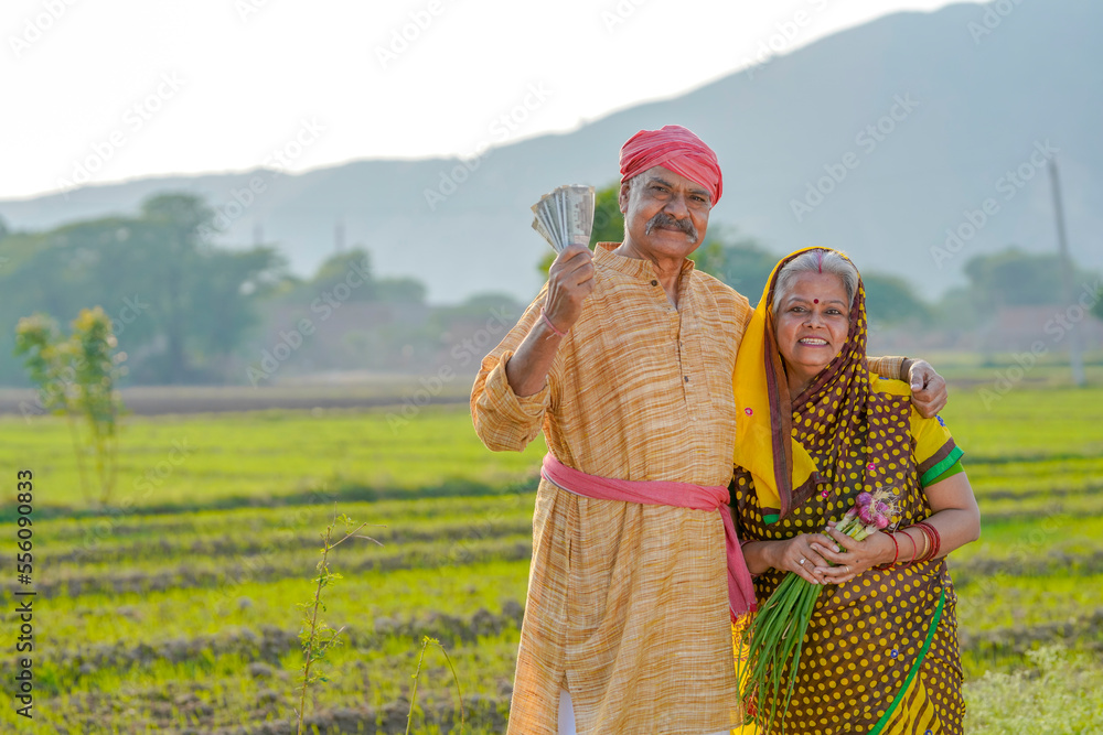 Indian farmer couple standing at agriculture field and showing rupees ...