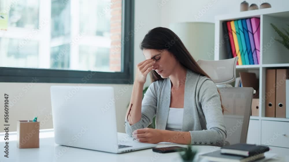 Video of exhausted young business woman with headache while working with laptop in the office. Video of exhausted young business woman with headache while working with laptop in the office.