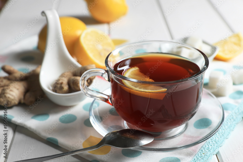 Cup of delicious ginger tea, sugar cubes and lemons on white wooden table, closeup Cup of delicious ginger tea, sugar cubes and lemons on white wooden table, closeup